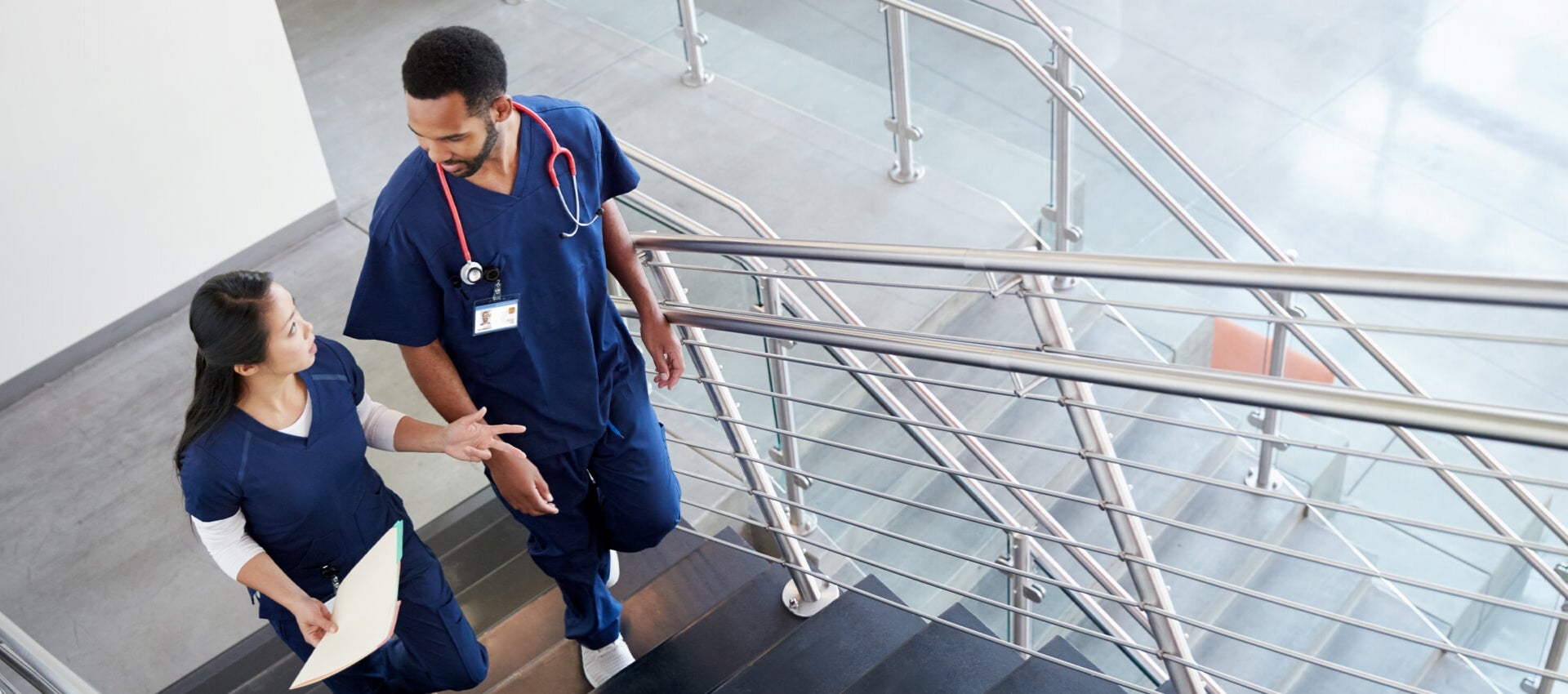 Nurses converse while ascending staircase.