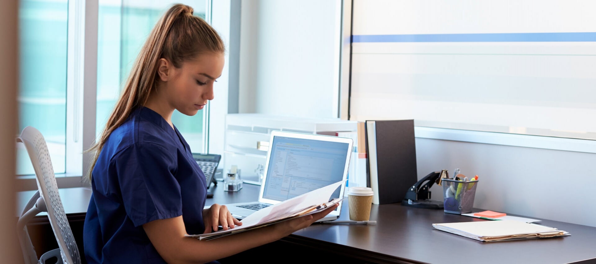 Nurse works to complete her coursework in an office.